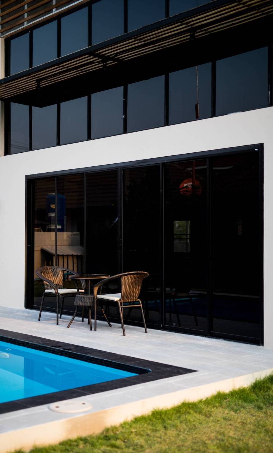 chairs-table-by-swimming-pool-against-building